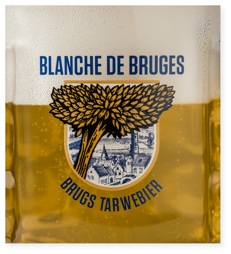 Bière Blanche de Bruges dans un verre avec logo et étiquette illustrée.